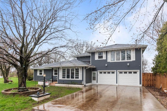 split level home with concrete driveway, a front yard, fence, and a garage