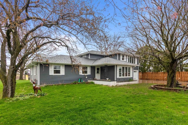 back of house featuring a shingled roof, a yard, and fence