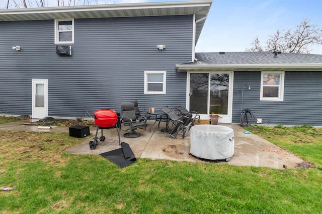 back of property with a yard, roof with shingles, and a patio area