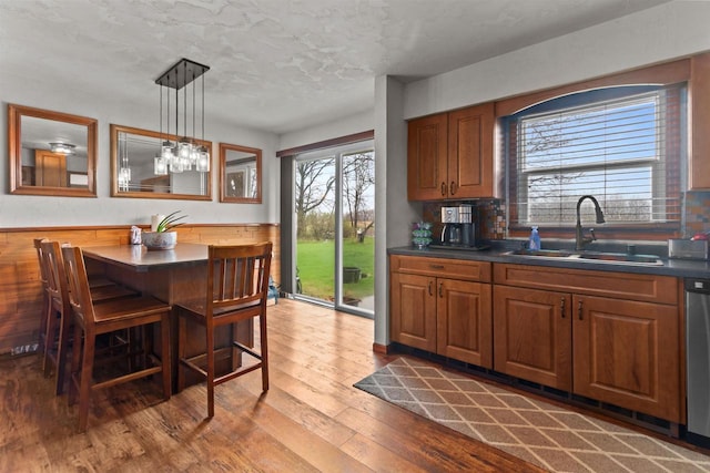 kitchen with dark countertops, a sink, a kitchen breakfast bar, brown cabinets, and hardwood / wood-style floors