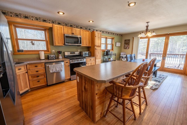 9327 Strong Rd, Argonne, WI 54511 - kitchen featuring a center island, a chandelier, a kitchen breakfast bar, light wood-style floors, and appliances with stainless steel finishes