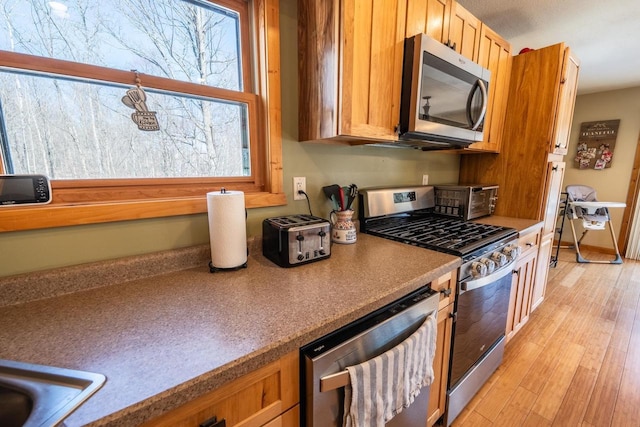9327 Strong Rd, Argonne, WI 54511 - kitchen with brown cabinets, a toaster, light wood finished floors, and appliances with stainless steel finishes