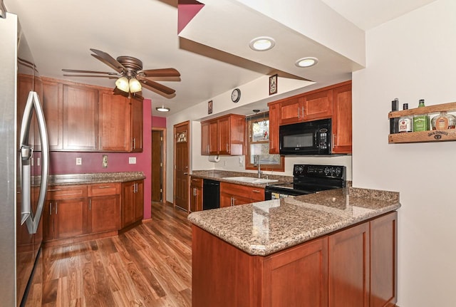 kitchen with light wood-style flooring, a sink, light stone countertops, ceiling fan, and black appliances