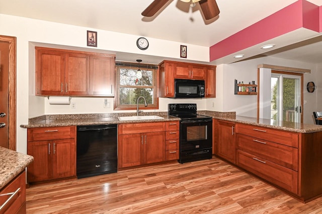 kitchen featuring a sink, a peninsula, black appliances, ceiling fan, and light wood finished floors