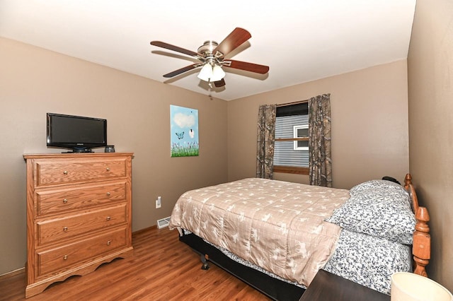 bedroom with baseboards, a ceiling fan, visible vents, and wood finished floors