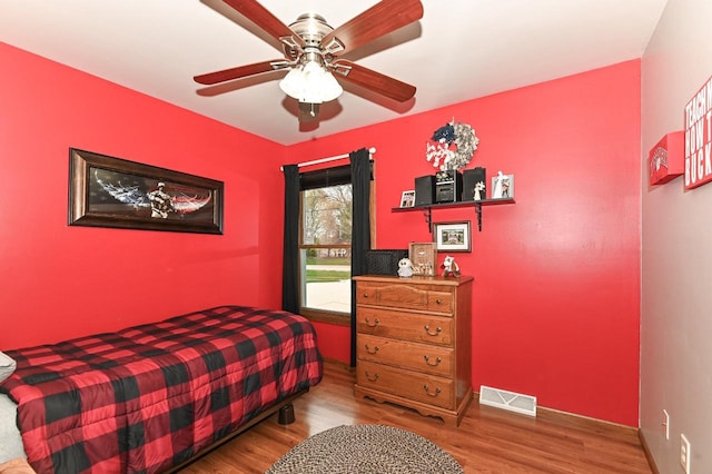 bedroom with ceiling fan, baseboards, visible vents, and wood finished floors