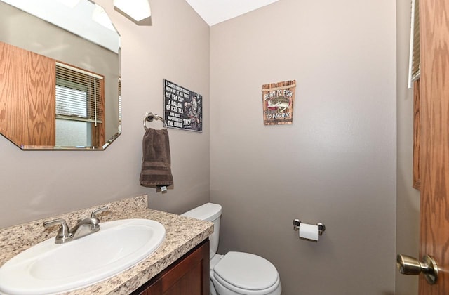half bathroom featuring vanity and toilet