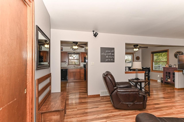 living room featuring baseboards, a ceiling fan, visible vents, and wood finished floors