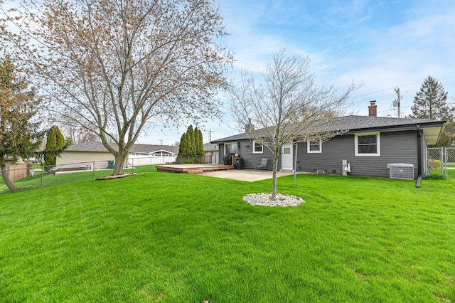 rear view of house featuring central AC, a chimney, a lawn, a fenced backyard, and a patio area