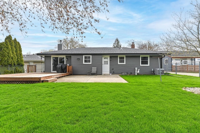 back of house with central AC unit, fence, a yard, and a chimney