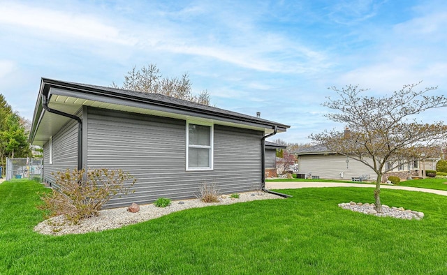 view of home's exterior featuring fence and a lawn