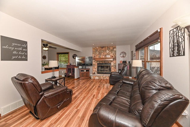 living room featuring a ceiling fan, visible vents, light wood-style flooring, and a fireplace