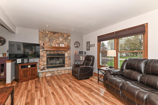 living room featuring a stone fireplace and light wood-style floors