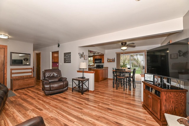 living room featuring light wood finished floors and a ceiling fan