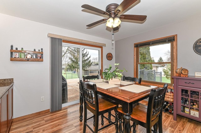 dining space featuring light wood-type flooring, a ceiling fan, and a healthy amount of sunlight