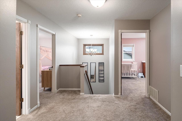 1218 Red Cedar Ct, Onalaska, WI 54650 - corridor with carpet flooring, an upstairs landing, a notable chandelier, a textured ceiling, and visible vents