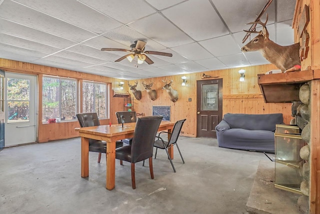 7589 Nose Lake Rd, Rhinelander, WI 54501 - dining space featuring a drop ceiling, ceiling fan, wood walls, and concrete floors