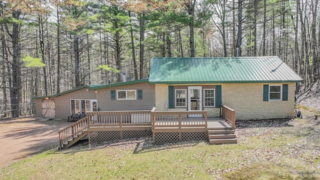 7589 Nose Lake Rd, Rhinelander, WI 54501 - rear view of house with metal roof, a wooden deck, stone siding, and a lawn