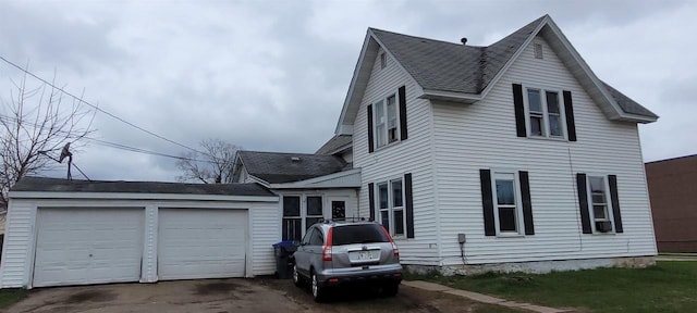 view of side of property featuring roof with shingles and a detached garage