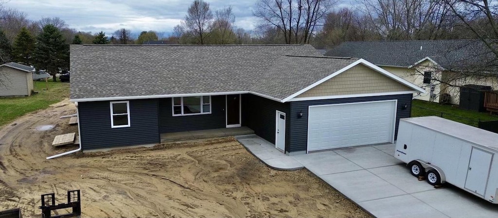 ranch-style house featuring an attached garage, concrete driveway, and a shingled roof