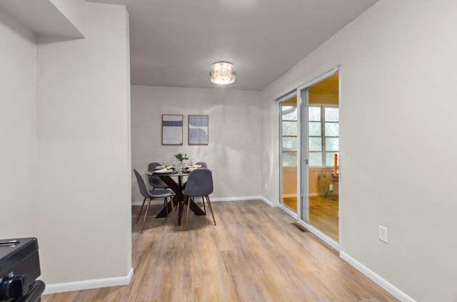 dining area with visible vents, light wood-style flooring, and baseboards
