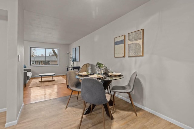 dining space featuring light wood finished floors and baseboards