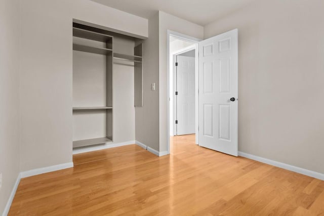 unfurnished bedroom featuring baseboards, light wood-type flooring, and a closet
