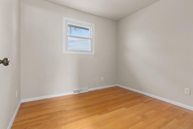 spare room with light wood-style floors, visible vents, and baseboards