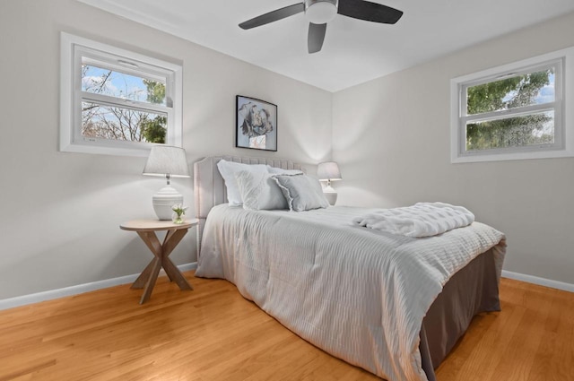 bedroom featuring baseboards, multiple windows, light wood-style flooring, and ceiling fan
