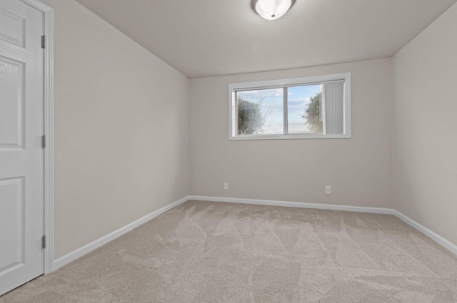 spare room with carpet flooring, baseboards, and lofted ceiling