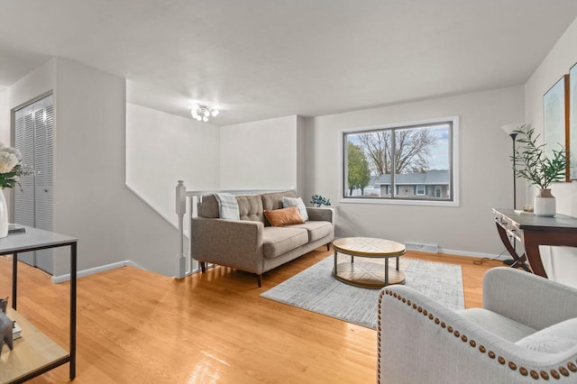 living room featuring light wood finished floors, visible vents, and baseboards