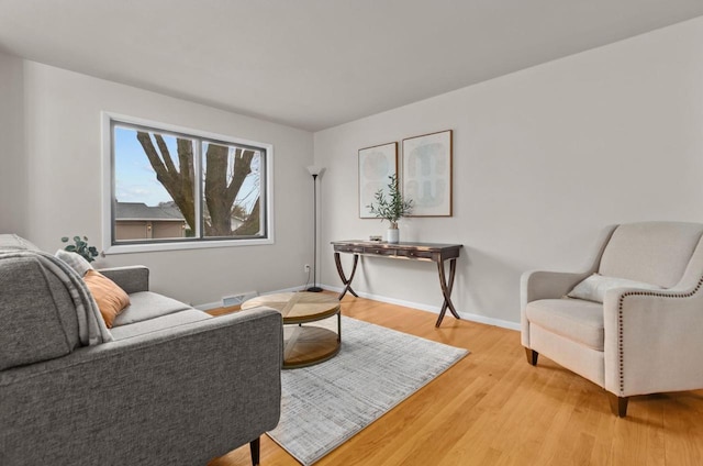 living area with light wood-style flooring, baseboards, and visible vents