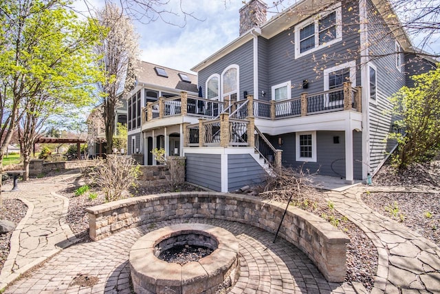2704 Kettle Ct, West Bend, WI 53090 - rear view of house with a patio area, stairway, a wooden deck, a chimney, and an outdoor fire pit