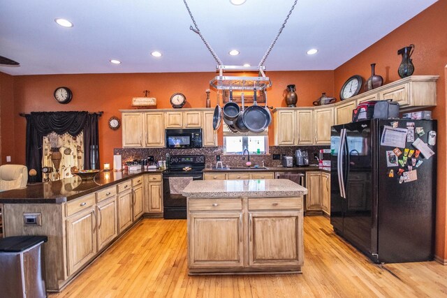 2704 Kettle Ct, West Bend, WI 53090 - kitchen with a peninsula, light wood finished floors, black appliances, a kitchen island, and tasteful backsplash