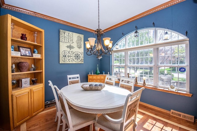 2704 Kettle Ct, West Bend, WI 53090 - dining area with ornamental molding, an inviting chandelier, visible vents, and wood finished floors