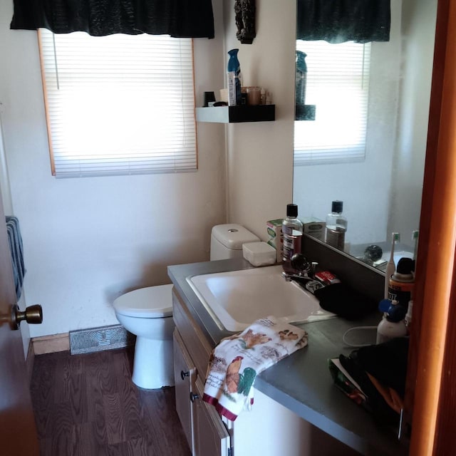 bathroom featuring toilet, baseboards, vanity, and wood finished floors