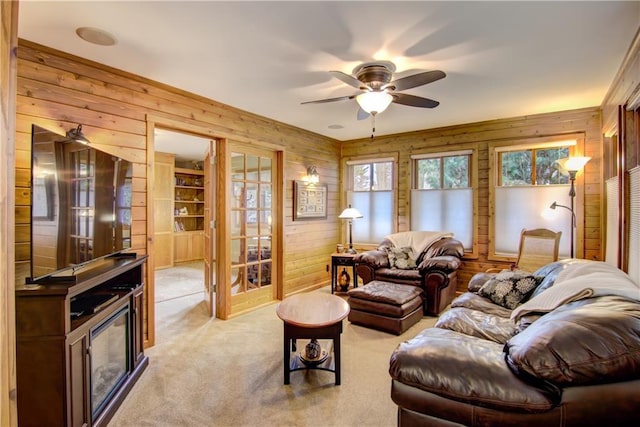 living room with light carpet, wooden walls, and a ceiling fan