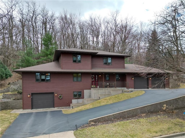 prairie-style house featuring roof with shingles, a porch, aphalt driveway, and a garage