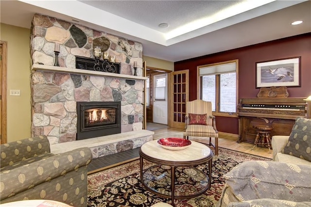living room with a stone fireplace, recessed lighting, and wood finished floors
