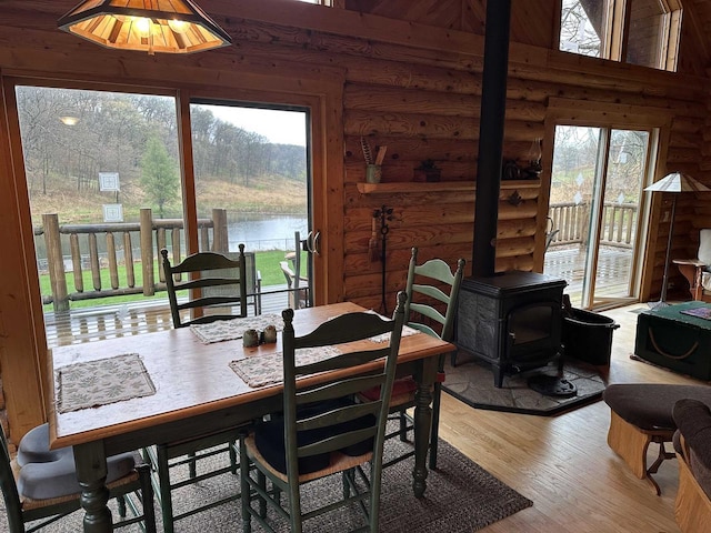 dining space featuring a wealth of natural light, a wood stove, log walls, and wood finished floors