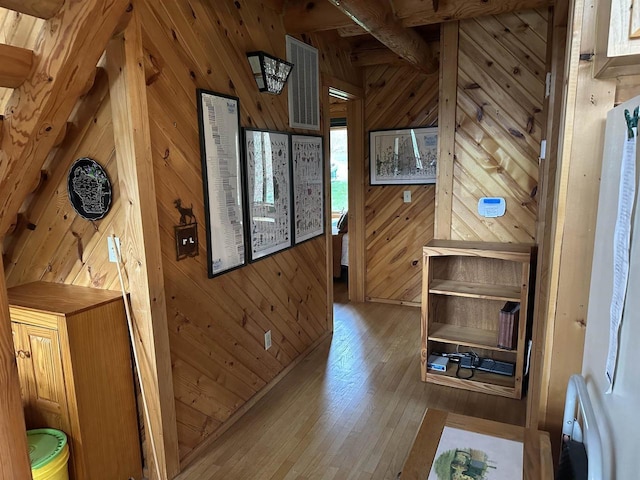 corridor featuring hardwood / wood-style flooring, wood walls, and visible vents