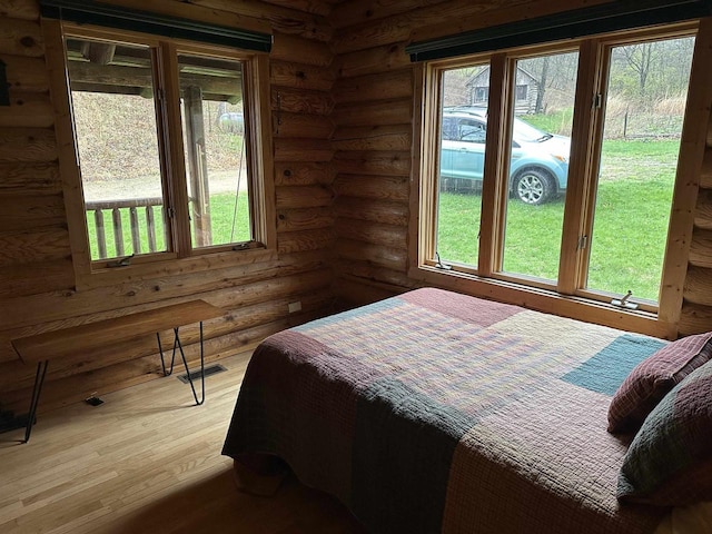 bedroom with light wood-type flooring, rustic walls, and visible vents