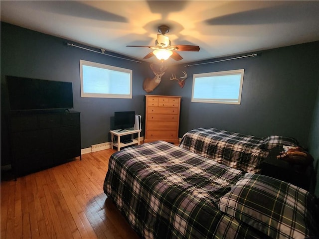 bedroom featuring baseboards, hardwood / wood-style floors, and a ceiling fan