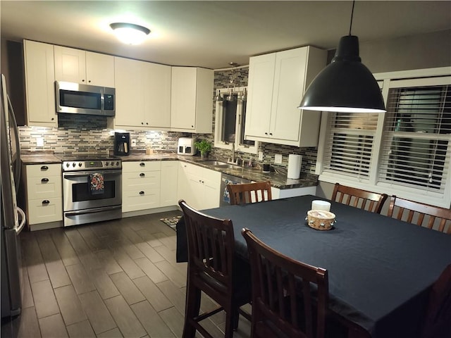 kitchen with white cabinets, decorative backsplash, stainless steel appliances, and a sink