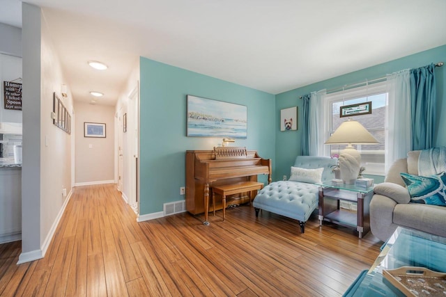 sitting room featuring baseboards, light wood-style floors, and visible vents