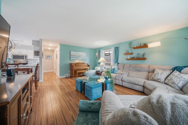living room with baseboards, visible vents, and light wood-style floors