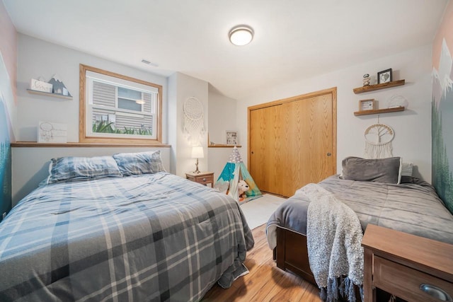 bedroom with a closet, light wood-type flooring, and visible vents