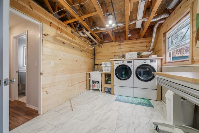 laundry area with laundry area, wood walls, and washer and dryer