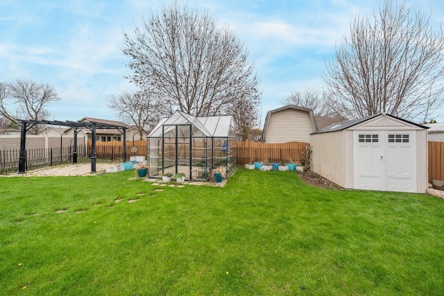 view of yard featuring a greenhouse, an outbuilding, and a fenced backyard