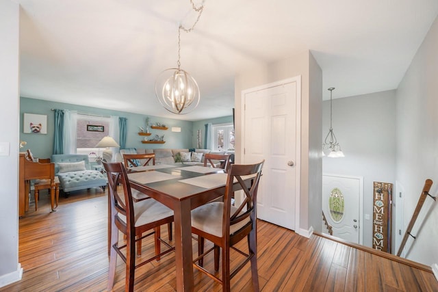 dining room featuring an inviting chandelier, hardwood / wood-style flooring, and baseboards